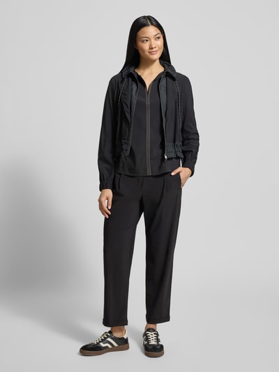 Kobiece model prezentuje Blazer mit Stehkragen od Marc Cain, czarny materiał, regular fit, tunel w talii, kieszenie, widok z przodu, pełna sylwetka.