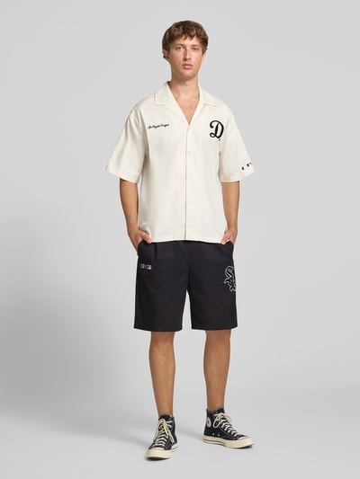 Männermodel trägt Relaxed Fit Shorts aus reiner Baumwolle von Champion in Schwarz mit elastischem Bund, Logo-Stitching, Ganzkörperansicht von vorne.