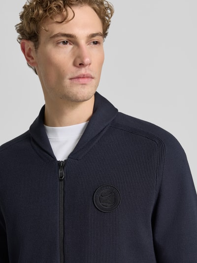 Męski model nosi kardigan rozpinany o kroju regular fit z mieszanki wiskozy model 'KN_UNION FZ' od BOSS Green, ciemnogranatowa faktura, zbliżenie na górną część ciała