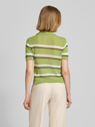 Frauenmodel trägt Slim Fit Poloshirt in Strick-Optik Modell 'Verdi' von Mango in Grün-Weiß-Beige, kurzärmelig, Material-Mix, Ganzkörperansicht Rückansicht.
