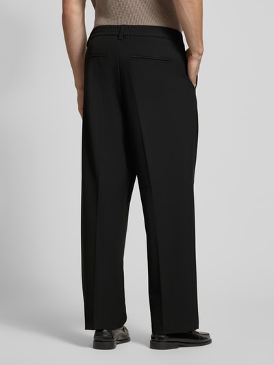 Männermodel trägt Straight Fit Hose mit Viskose-Anteil Modell 'Grant' von Casual Friday in Schwarz, Bügelfalten, Rückansicht, Nahaufnahme Oberkörper, elastischer Bund, Teilelastischer Bund, Produktdetails: elastischer Material-Mix, Knopf- und Reißverschluss, Bundweite 43 cm, Innenbeinlänge 74 cm.