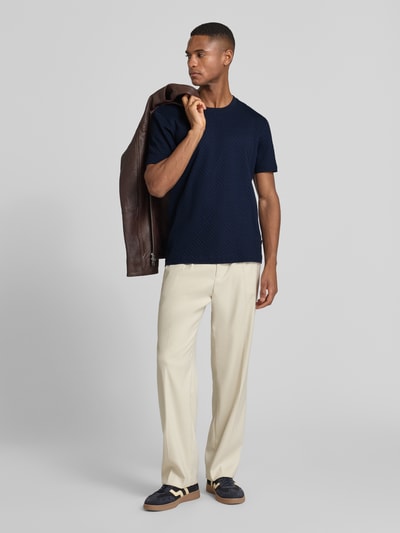 Männermodel trägt T-Shirt mit geripptem Rundhalsausschnitt von JOOP! Collection aus reiner Baumwolle, Regular-Fit, dunkelblau, Ganzkörperansicht von vorne.