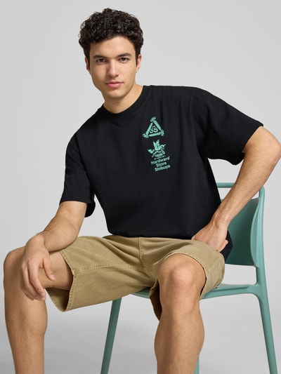 Męski model nosi T-Shirt mit Print und Rundhalsausschnitt od Edwin, bawełna, krój relaxed fit, długość tyłu 72 cm, widok z przodu, zbliżenie na górę ciała.