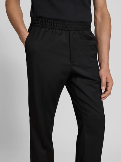 Männermodel trägt Straight Fit Stoffhose mit Woll-Anteil von Filippa K in Schwarz, elastischer Bund, Bundfalten, Nahaufnahme Oberkörper
