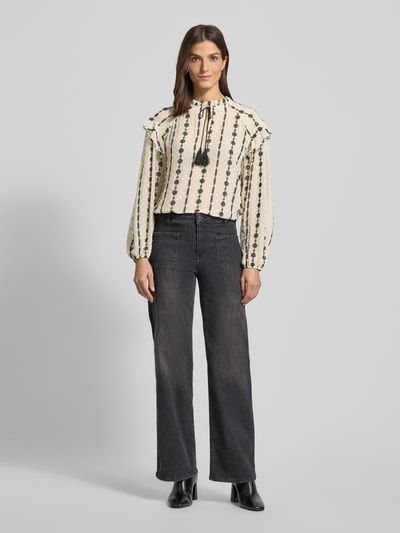 Frauenmodel trägt Regular Fit Bluse mit Stitchings von More & More, Schlüsselloch-Ausschnitt, Schnürung, Creme mit schwarzen Details, Ganzkörperansicht von vorne. Rückenlänge 62 cm, Ärmellänge 59 cm, Größe 36.