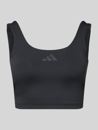 Produktfoto, Crop Top mit Label-Print od adidas Sportswear, czarny kolor, dekolt w łódkę, dopasowany krój, mieszanka materiałów z dodatkiem streczu, nadruk z logo na środku, długość tyłu przy rozmiarze S: 21 cm.