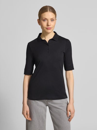 Modelka kobieca ma na sobie Slim Fit Poloshirt mit Knopfleiste und 1/2-Arm od Christian Berg Woman z bawełny, krój slim fit, listwa guzikowa, rękaw o dł. 1/2, długość tyłu w rozmiarze 36: 61 cm, kolor czarny, gładka tekstura, całkowity przód.