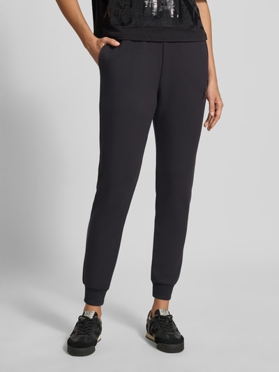 Kobiece model prezentuje Slim Fit Sweatpants aus Viskose-Mix od Armani Exchange, czarne, krój slim fit, elastyczne wykończenia, elastyczny pas, mieszanka wiskozy, długość wewnętrzna nogawki w rozmiarze S: 74 cm, zdjęcie całego ciała z przodu.