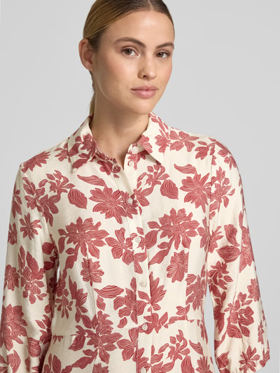 Frauenmodel trägt Hemdblusenkleid aus Viskose-Mix Modell 'Vildana' von MSCH Copenhagen im Allover-Look mit Knopfleiste und 3/4-Arm, cremefarben mit roten Blumen, Nahaufnahme Oberkörper. Rückenlänge bei Größe S: 138 cm, Brustweite: 47 cm, Ärmellänge: 50 cm.