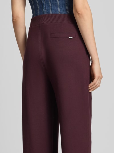 Frauenmodel trägt bordeauxrote Relaxed Fit Sweathose aus Viskose-Mix Modell 'Style.Maine' von Brax, glatte Textur, Detailaufnahme Rückansicht, Damen Sweathose von Brax.