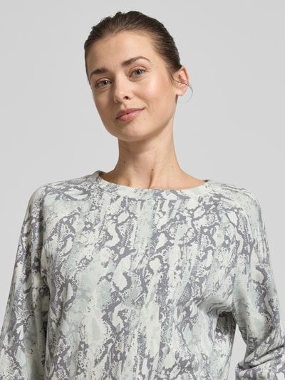 Frauenmodel trägt Comfort Fit Sweatshirt aus Baumwoll-Mix von Tom Tailor Denim mit abstraktem Allover-Muster in Grau und Hellgrün, Nahaufnahme Oberkörper.
