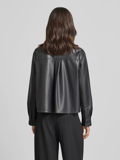 Modelka nosi Relaxed Fit Hemdjacke in Leder-Optik Modell 'Zeather' od Someday, czarny materiał skóropodobny, wykładany kołnierz, listwa guzikowa, długość tyłu w rozmiarze 36: 52 cm, szerokość ramion w rozmiarze 36: 40 cm, szerokość klatki piersiowej w rozmiarze 36: 65 cm, długość rękawów w rozmiarze 36: 63 cm, całkowity widok z tyłu.
