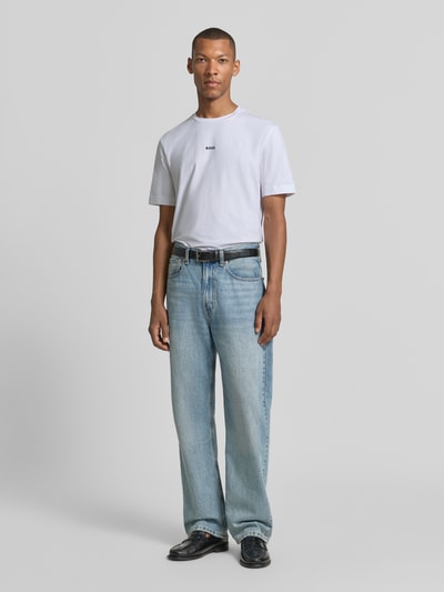 Männermodel trägt T-Shirt mit Label-Print von BOSS, weiß, schlichte Baumwoll-Elasthan-Textur, Regular Fit, Ganzkörperansicht von vorne, Herren T-Shirt von BOSS, Rundhalsausschnitt, Rückenlänge bei Größe M: 70 cm.