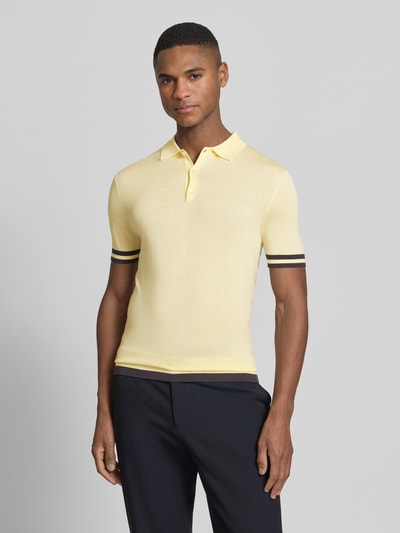 Męski model nosi Slim Fit Poloshirt aus Lyocell-Seide-Mix von Guess z kontrastowymi paskami, kolor żółty, krój slim fit, przód, ujęcie całopostaciowe.