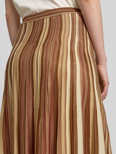 Vrouwenmodel draagt Maxirok uit viscose in all-over look van Bash, A-lijn, elastische band, bruin-beige strepen, detailopname rug.
