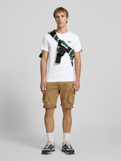 Mannenmodel draagt T-Shirt met Logo en Rundhalsausschnitt van Alpha Industries in wit, regular fit, katoen, logoprint, vooraanzicht hele lichaam.