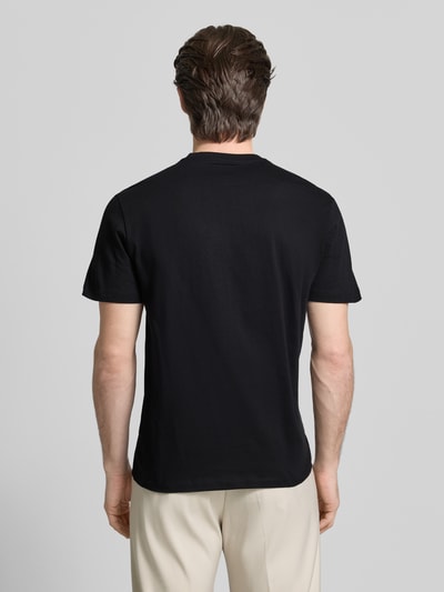 Męski model nosi T-shirt mit Label-Detail von GUESS, czarny, bawełna, krój regular fit, okrągły dekolt, długość tyłu 69 cm, Ganzkörperansicht Rückansicht.