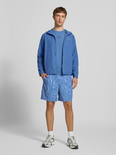 Männermodel trägt Regular Fit Trainingsjacke mit Kapuze von Nike in Blau mit glatter Textur, Herren Trainingsjacke, Ganzkörperansicht von vorne.