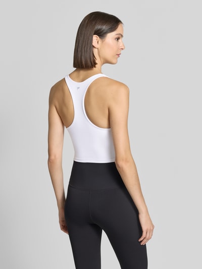 Vrouwenmodel draagt Cropped Top met geïntegreerde cups van Fabletics, dames top met geïntegreerde cups, kort fit, slim fit, ronde hals, ruglengte maat S 36 cm, zwarte en witte tinten, gladde textuur, Ganzkörperansicht Rückansicht.