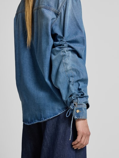 Frauenmodel trägt Oversized Jeansbluse aus Lyocell-Baumwoll-Mix Modell 'JUZY' von Essentiel Antwerp, mittleres Blau, Ganzkörperansicht Rückansicht. Damen Langarmbluse.