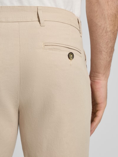 Männermodel trägt Slim Fit Chinoshorts aus Baumwoll-Mix Modell 'SLIM-LUTON' von SELECTED HOMME, efekt: jednolity kolor, aplikacja z metką, szlufki na pasek, zapięcie na guzik i ukryty zamek błyskawiczny, wpuszczane kieszenie, z tyłu kieszeń z guzikiem, wykończenie materiału: tkana faktura, mieszanka bawełny, krój slim fit, detal: widoczny szew; zbliżenie na tył.