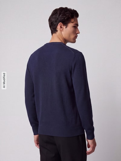 Männermodel trägt dunkelblauen Regular Fit Pullover aus reiner Baumwolle Modell 'TORINO' von Selected, Herren Pullover, Ganzkörperansicht Rückansicht, KI-modifiziertes Bild.