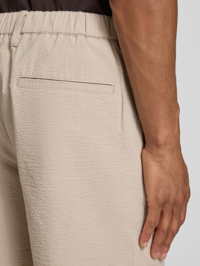 Mężczyzna nosi Regular Fit Bermudas aus Baumwoll-Mix Modell 'KARL' von SELECTED HOMME, beżowy wzór w paski, faktura seersucker, wpuszczana kieszeń, mieszanka bawełny, detailaufnahme tylnej części.