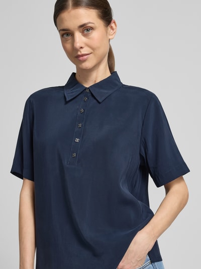 Frauenmodel trägt Relaxed Fit Poloshirt aus Viskose-Mix Modell 'Mindy' von My Essential Wardrobe in Dunkelblau, Nahaufnahme Oberkörper. Damen Poloshirt mit Polokragen, kurzärmelig, Rückenlänge bei Größe 36: 60 cm, glatte Textur.