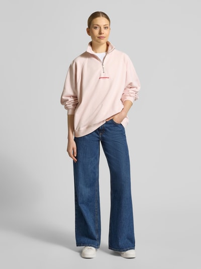 Frauenmodel trägt Oversized Sweatshirt aus reiner Baumwolle von Armedangels in Optik: Unifarben mit Label-Print, Troyer-Kragen, Langarm und Raglanärmel, Materialverarbeitung: Sweat, Ganzkörperansicht von vorne.