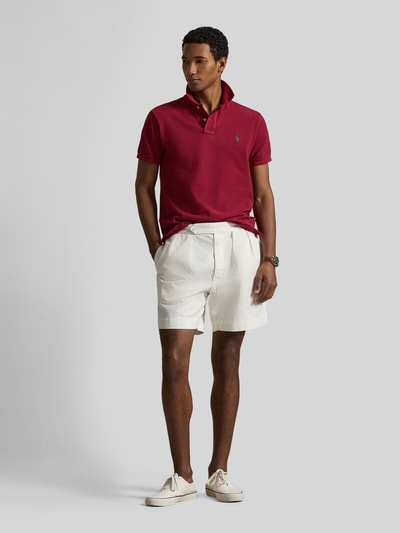 Mannelijk model draagt Regular Fit Poloshirt uit zuivere katoen van Polo Ralph Lauren, effen, piquéstructuur, korte mouw, logo-accent, polo kraag, V-hals, korte knoopsluiting, geribde mouwboorden, asymmetrisch met zijsplitten, voorkant totaalbeeld.
