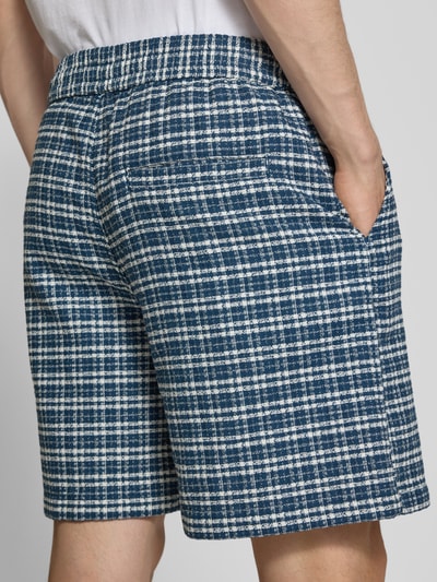 Männermodel trägt Shorts mit Strukturmuster Modell 'Kander' von Carhartt Work In Progress in Blau-Weiß, Paspeltasche, Ganzkörperansicht Rückansicht