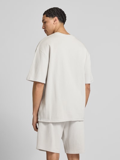 Männermodel trägt Oversized T-Shirt mit Strukturmuster von Pegador aus Baumwoll-Mix, Oversized-Fit, Rundhalsausschnitt, Logo-Stitching, Rückenlänge 71 cm, helle Farbe, Ganzkörperansicht Rückansicht.