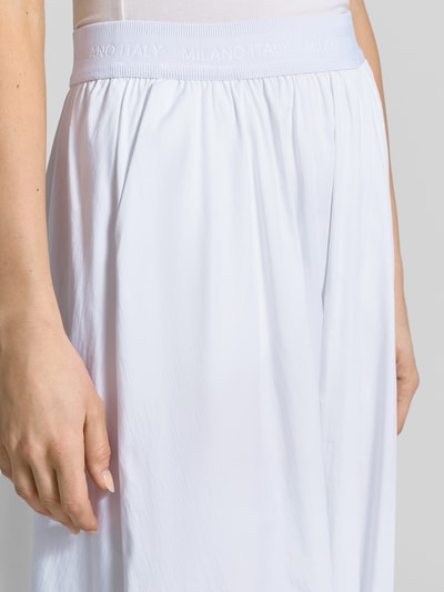 Kobiece model prezentuje spódnica midi z mieszanki bawełny z dodatkiem streczu od Milano Italy, linia a, model 'SNOS', elastyczny pas z logo, detal z logo, szerokość w rozmiarze 36: 34 cm, całkowita długość w rozmiarze 36: 82 cm, zbliżenie na górną część przodu