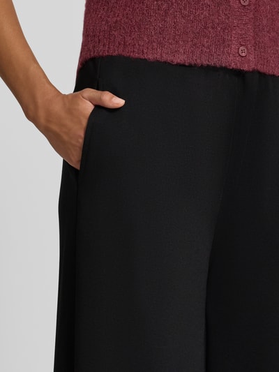Frauenmodel trägt Wide Fit Hose mit Viskose-Anteil Modell 'Nanni' von FREE/QUENT, schwarze Farbe, strukturierte Oberfläche, elastischer Bund, verkürzte Passform, Nahaufnahme Oberkörper.