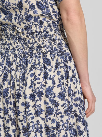 Frauenmodel trägt Maxirock aus Viskose im Allover-Look Modell 'Myra' von LOLLYS LAUNDRY, florales Design in Blau und Creme, Nahaufnahme Oberkörper. Damen Maxirock, Reine Viskose, A-Linie, Bundweite bei Größe S: 42 cm, Gesamtlänge bei Größe S: 92 cm.