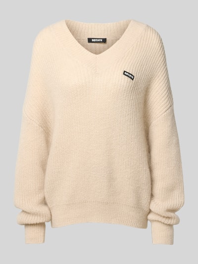 Produktfoto, Oversized Pullover mit Woll-Anteil von ROTATE im cremefarbenen Material-Mix mit Strick-Optik und Logo-Patch, V-Ausschnitt.