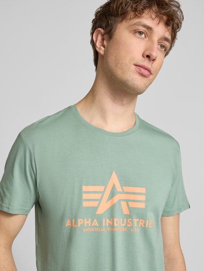 Mannenmodel draagt T-shirt met Label-Detail model 'BASIC' van Alpha Industries in mintgroen, puur katoen, recht model, ronde hals, nahaufnahme bovenlichaam.