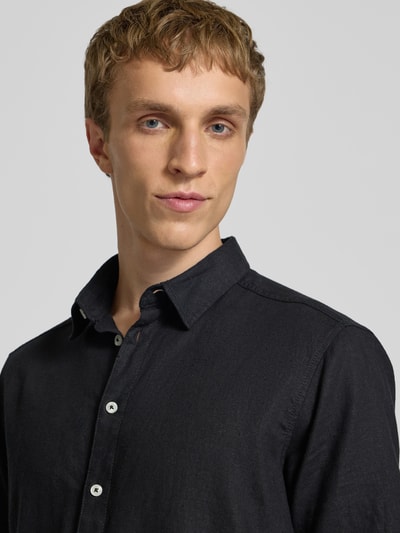 Männermodel trägt Slim Fit Leinenhemd mit Viskose-Anteil Modell 'Bobby' von Blend in Schwarz, sichtbarer Kentkragen und Knopfleiste, Nahaufnahme Oberkörper. Leinen-Mix, Kurzarm, modernes Design.