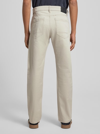 Mężczyzna nosi Regular Fit Chino aus Baumwoll-Mix von s.Oliver RED LABEL, jasnobeżowy kolor, krój regular fit, 5 kieszeni, label patch, bawełniany materiał, zdjęcie całej sylwetki z tyłu.