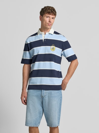 Męski model nosi Regular Fit Poloshirt mit Label-Stitching von MCNEAL z bawełny, listwa guzikowa, długość tyłu w rozmiarze M 66 cm, Ganzkörperansicht von vorne.