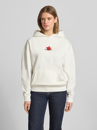 Vrouwenmodel draagt Oversized Hoodie met Label-Stitching model 'MODRA' van Pegador in crèmekleur, katoenmix, kangoeroezak, oversized fit, voorkant volledig zichtbaar, opname van voren.