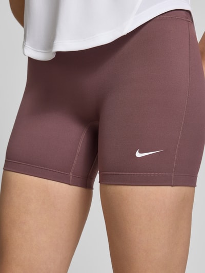 Frauenmodel trägt Radlerhose mit Logo und elastischem Bund von NIKE TRAINING, Material-Mix mit Stretch-Anteil, körpernahe Passform, Ganzkörperansicht von vorne.