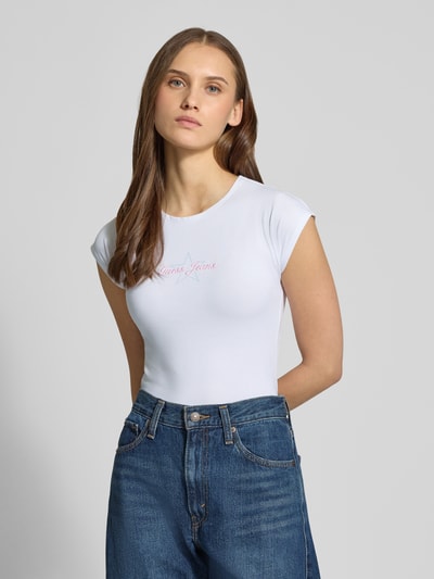Frauenmodel trägt Slim Fit T-Shirt mit Logo-Stitching von Guess Jeans aus elastischem Baumwoll-Mix, Weiß, Rundhalsausschnitt, Nahaufnahme Oberkörper.