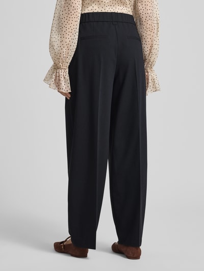 Frauenmodel trägt Barrel Fit Hose Modell 'Moira Bloom' von OPUS PANTS aus Baumwoll-Mix mit Stretch, schwarze Farbe, Bügelfalten, Ganzkörperansicht Rückansicht.