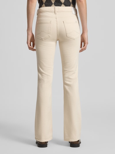 Frauenmodel trägt Flared Fit Jeans im 5-Pocket-Design Modell 'Shelby' von Mustang aus elastischem Baumwoll-Mix in Beige, Ganzkörperansicht Rückansicht.