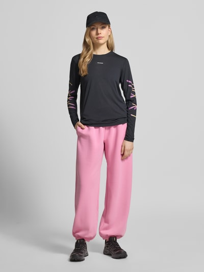 Kobieta modelka nosi Funktionsshirt mit Logo Modell 'Kout' od Salomon, czarny kolor, krój regular fit, dekolt okrągły, przód, długość pleców w rozmiarze S 58 cm, Ganzkörperansicht von vorne.