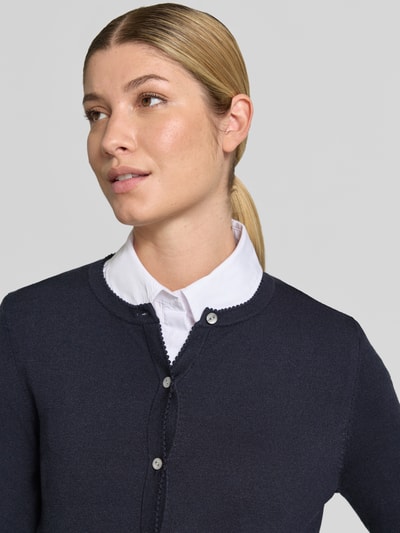 Vrouwenmodel draagt Regular Fit gebreid jack uit Viscosemix met geschulpte zoom van Christian Berg Woman, knoopsluiting, Lange mouw, ribboorden, ruglengte maat S 56 cm, mouwlengte maat S 61 cm, Nahaufnahme bovenlichaam.