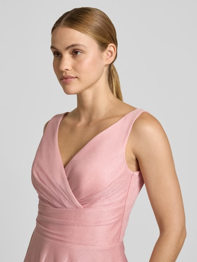 Frauenmodel trägt Knielanges Cocktailkleid mit V-Ausschnitt von TROYDEN COLLECTION aus rosafarbenem Chiffon, Taillierter Schnitt, breite Träger, Nahaufnahme Oberkörper.