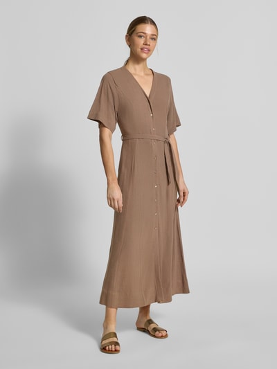 Modelka kobieca nosi Regular Fit Leinenkleid mit V-Ausschnitt Modell 'VIVA' od Selected Femme, jednolity kolor, długość maxi, pasek, bez rękawów, tkanina wiskozowo-lniana, wizualizacja z przodu całej sylwetki.