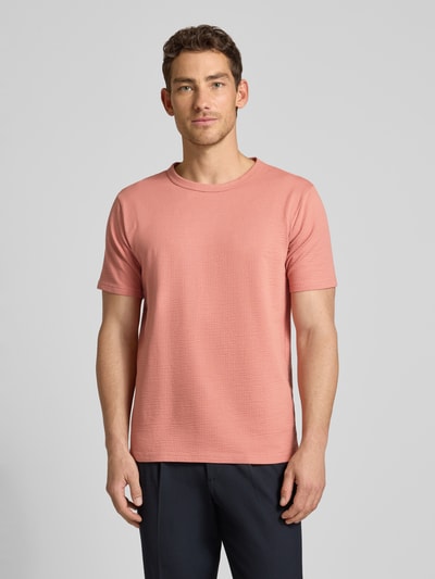 Männermodel trägt Regular Fit T-Shirt aus Baumwoll-Mix Modell 'SANDER' von SELECTED HOMME in Rosa, Seersucker-Textur, Ganzkörperansicht von vorne.